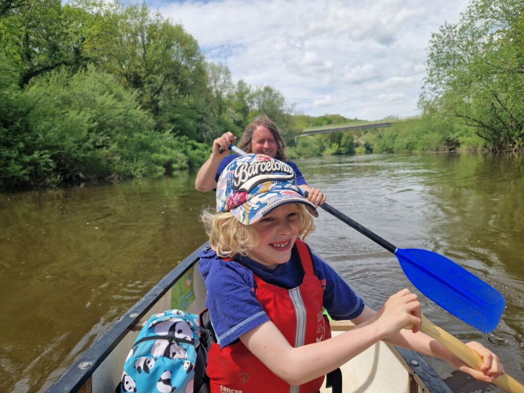 River severn canoes: father and son on a canoe on a river, look happy, smiling away.