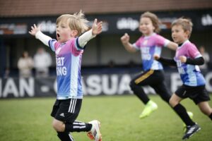 Children playing football celebrating scoring a goal