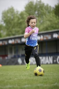Girl running with a football at Platform Sports Coaching for children's classes and holiday camps
