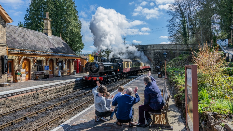 Family waving at a steam train arriving at Severn Valley Railway